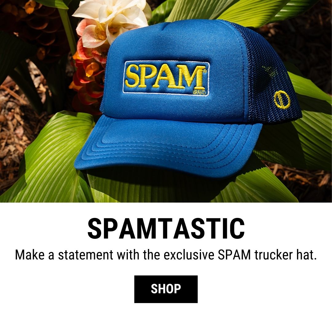 A blue trucker hat featuring the yellow and blue SPAM logo prominently on the front. The hat is placed on green leaves, with bright red and white flowers in the background. The text below reads "SPAMTASTIC" and "Make a statement with the exclusive SPAM trucker hat." A "SHOP" button is displayed beneath the text.